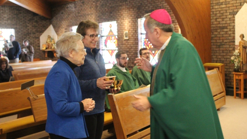 Bishop Robert J. McClory accepts the offertory gifts at St. Stephen, Martyr's closing Mass on Feb. 15 from two specially chosen parishioners, Isabel Ramirez (left), age 100, who attended the parish's first Mass 57 years ago, and Ann Janda, the first baby baptized in the new church building 55 years ago. (Marlene A. Zloza photo)