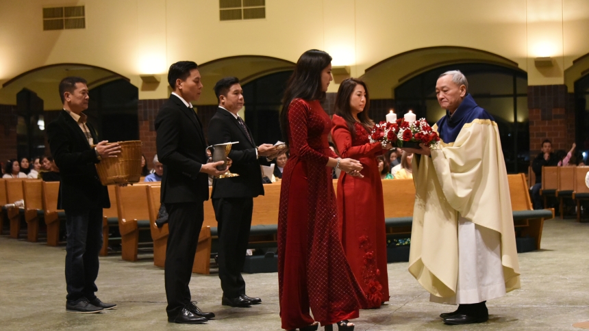 A group of Vietnamese Catholics present flowers and Offertory gifts to Society of the Divine Word Father Nhan Tran (right) during Mass at a Tết, or Lunar New Year's gathering, which included a fellowship meal at St. Michael the Archangel parish in Schererville on Jan. 26. The Vietnamese observance of the Tết is the most prominent holiday in that culture, and Catholics celebrate it as not only a time for gathering and wishing for prosperity, but also a time to give thanks to God for His many blessings. (Anth