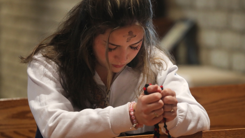 A young woman prays with a rosary following Ash Wednesday Mass at Sacred Heart Church in Prescott, Ariz., March 5, 2025. (OSV News photo/Bob Roller)