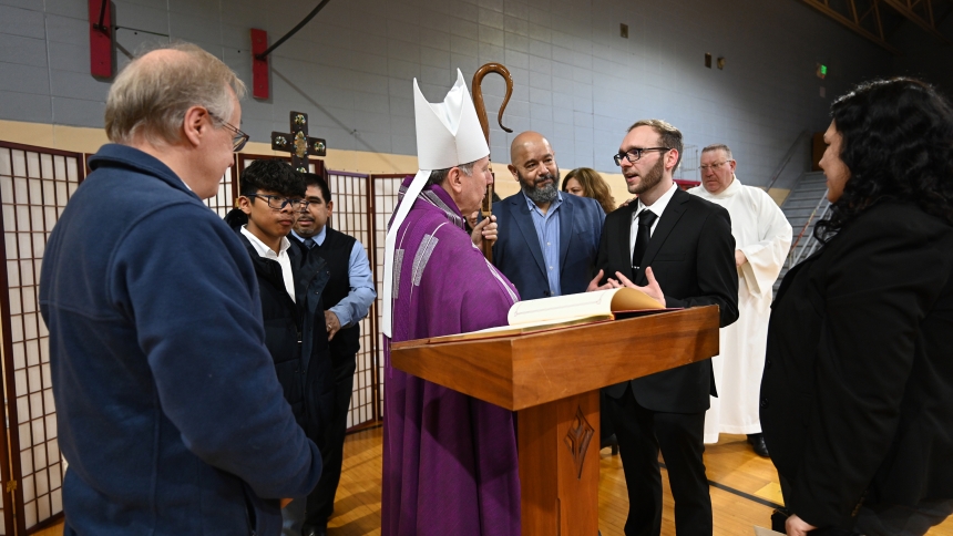 Bishop Robert J. McClory (center) converses with members of Sacred Heart, Whiting, as the diocesan shepherd signs the Book of the Elect, following the Rite of Election for Catechumens at the Cathedral of the Holy Angels in Gary on March 9. The Whiting faithful were among 94 catechumens and a full cathedral of family and friends ready to support their brothers and sisters in Christ. (Anthony D. Alonzo photo)