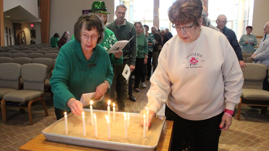 Parishioners Mary Ellen LaDuke (left) and Jeanne DeLasCasas place their candles in sand while others wait their turn at Holy Spirit in Winfield on March 17, the Feast of St. Patrick. After participating in a Service of Light, the congregation shared a corned beef and cabbage dinner with their One Catholic Family neighbors. (Marlene A. Zloza photo)