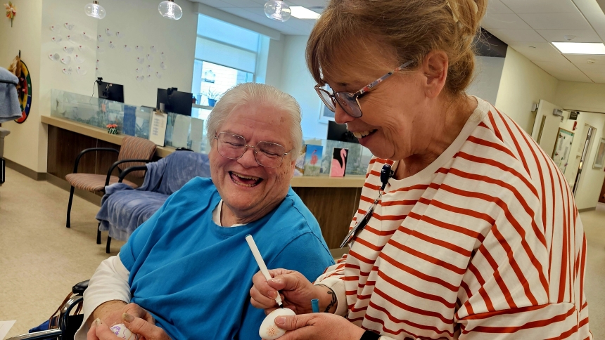 Debbie Martin shares a laugh with Franciscan PACE Activities Coordinator Paula Hedrich while coloring Easter eggs at the Michigan City location. 