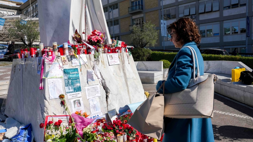 A woman stands near a statue of St. John Paul II outside Rome’s Gemelli hospital March 6, 2025, looking at messages and drawings for Pope Francis, who has been hospitalized there since Feb. 14, receiving treatment for double pneumonia. (CNS photo/Lola Gomez)