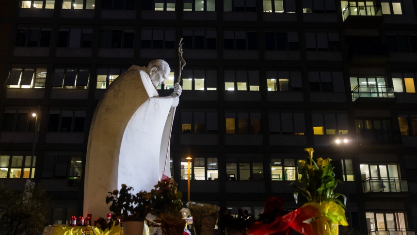 People pray near a statue of St. John Paul II outside Rome's Gemelli hospital where people have left drawings, votive candles, rosaries, flowers, cards for Pope Francis March 8, 2025. (CNS photo/Pablo Esparza)