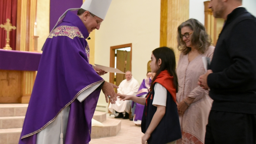 Bishop Robert J. McClory (left) presents an honorary certificate to American Heritage Girl Explorer Jane Swift (center), 9, as her parents Kathy and Mike Swift (at right) join her after the annual Diocese of Gary Catholic Committee Religious Emblem Mass on March 23 at St. Bridget church in Hobart. In his homily, the bishop praised the feats of faith accomplished by the girls, as well as attending Boy Scouts of America, and encouraged them to persevere in their belief. (Anthony D. Alonzo photo)