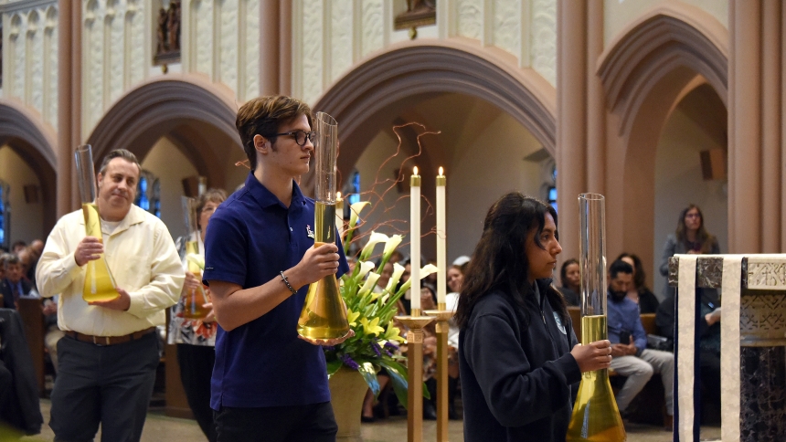 At the Cathedral of the Holy Angels (left to right) Sean Martin, diocesan coordinator of Catechesis and Faith Formation, Joe Bojda, a Marian Catholic High School junior, and Isabella Diaz, a St. John Bosco eighth-grader process holding glass vessels filled with the Oil of the Sick during the Chrism Mass in Gary on April 17. The service included the blessing of holy oils and consecration of sacred Chrism to be used for sacramental purposes, and a reaffirming of vows by priests before Bishop Robert J. McClor