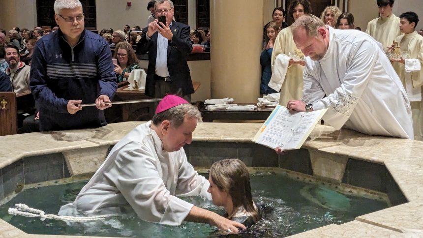 Amanda Alessi is immersed three times - in the name of the Father, and of the Son and of the Holy Spirit - during the East Vigil Mass at St. John the Evangelist in 2024. (Lynda J. Hemmerling photo)