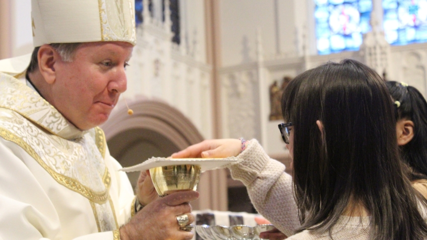 Bishop Robert J. McClory accepts the offertory gifts from Nataly Garcia of St. Mary in East Chicago and Cinthia Ortiz Lopez of St. Margaret Mary in Hammond, at the annual Mass for People with Disabilities on April 27 at the Cathedral of the Holy Angels in Gary. Not pictured is gift bearer Angela Darrol of Our Lady of Sorrows in Valparaiso. (Marlene A. Zloza photo)