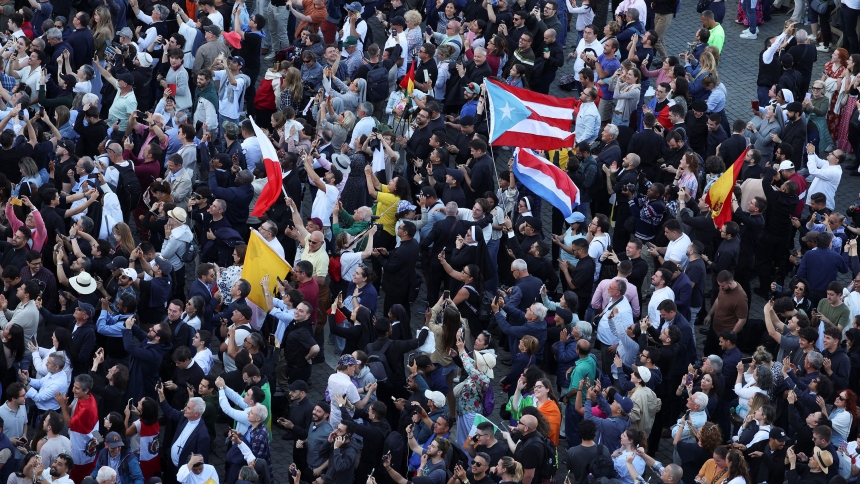 The crowd waves Puerto Rican flags and other flags in St. Peter's Square at the Vatican on the second day of the conclave as white smoke billows from the chimney indicating a new pope has been elected. (OSV News photo/Claudia Greco, Reuters)