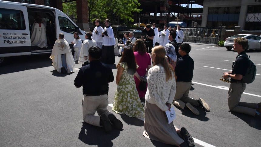 Young adults serving as "perpetual pilgrims" on the National Eucharistic Pilgrimage kneel on May 18, 2025, on the grounds of St. John the Evangelist Church in Indianapolis while the Eucharist is placed in the pilgrimage van. The pilgrimage, which started in Indianapolis, will cross 10 states, 20 dioceses and four Eastern Catholic eparchies before concluding June 22, the feast of Corpus Christi, in Los Angeles. (OSV News photo/Sean Gallagher, The Criterion)