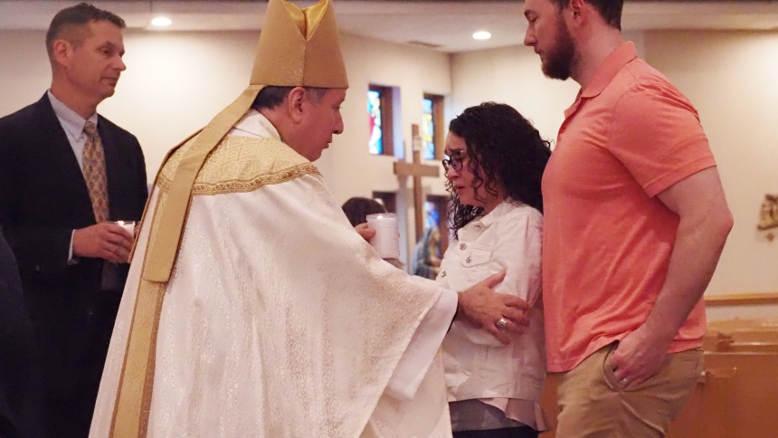 Vanessa and Ryan Lochow, St. James the Less parishioners, receive a candle from Bishop Robert J. McClory during the Mass of Remembrance for Bereaved Parents. (Mary Wellinski photo)