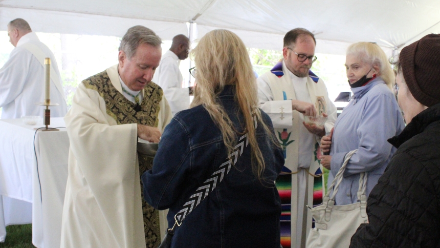 Bishop Robert J. McClory (left) and Father Jeffrey Burton distribute Holy Communion to congregants at the Memorial Day Mass hosted by the Diocese of Gary at St. John-St. Joseph Catholic Cemetery in Hammond on May 26. A sunny but cool day greeted those remembering loved ones and fallen soldiers at the liturgy. (Marlene A. Zloza photo)