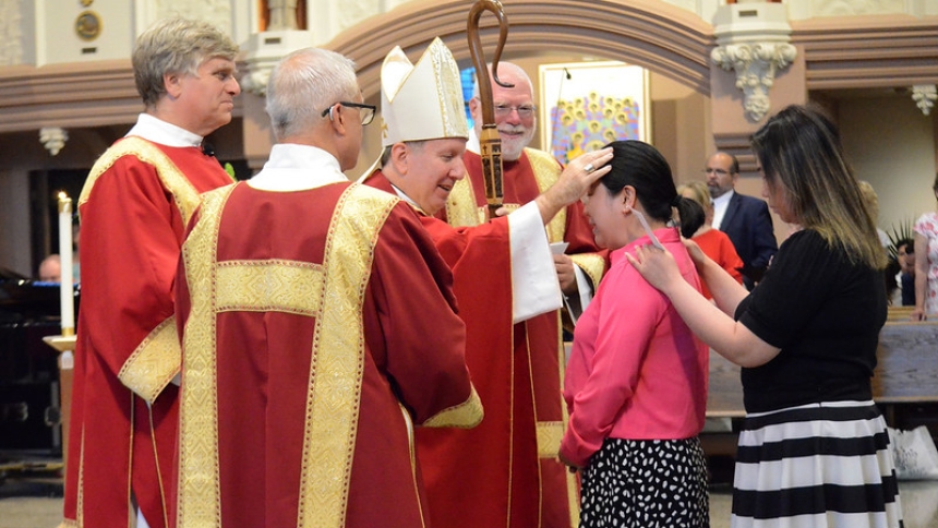 Bishop Robert J. McClory confirms adults at the Cathedral of the Holy Angels on Pentecost.