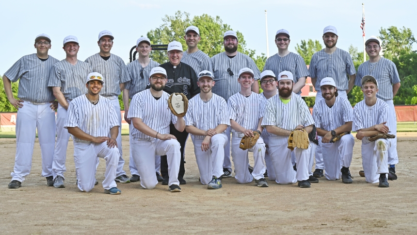 A team of Diocese of Gary seminarians (front row), gather near Bishop Robert J. McClory (center) and diocesan priests (back row) after earning a victory over the ordained in the second annual Collars vs. Scholars Classic event hosted by the Office of Vocations at the Andrean High School softball diamond in Merrillville on June 27. In the event to promote vocations and summer fun, the discerners flipped the script from last year's game in which the priests doubled the seminarians’ score. (Anthony D. Alonzo p