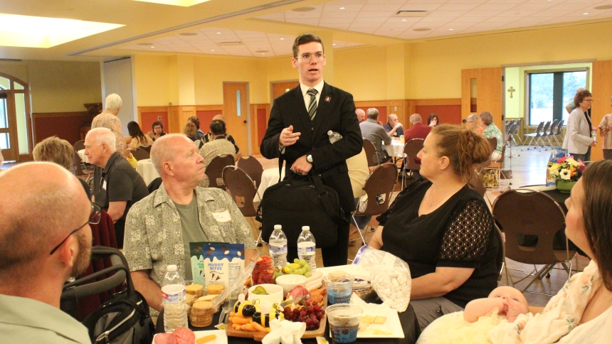 Guest speaker Leo Marquette (standing), a Diocese of Gary seminarian, chats with the Usdowski family, (from left) Rich, his father Rich, and mother, Shery, and wife Lynne with baby Annie, before the Theology Uncorked program on Pope Leo XIV at St. Michael the Archangel in Schererville on July 10. The younger Usdowski’s  St. Michael parishioners, invited the elder Usdowski’s, who attend St. Mary in Griffith, to the evening event featuring food, fellowship and an educational program. (Marlene A. Zloza photo)