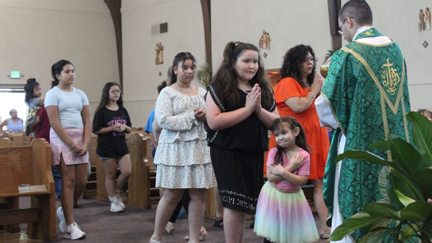 Distribution Holy Communion and blessings to young people, Father Ivan Alatorre celebrates the new Spanish-language Mass on July 27 at St. John Bosco in Hammond. Without any publicity other than outreach to parish school families and word of mouth, about 60 people have been attending weekly. (Marlene A. Zloza photo)