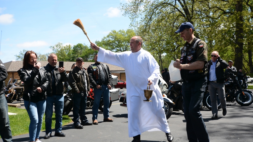 Father Mikolaj Markiewicz, outgoing superior of the Salvatorian Fathers at Our Lady of Czestochowa Shrine, blesses motorcyclists and their bikes at the order’s campus in Merrillville on May 5, 2024.  At the end of this month, the priest affectionately called “Father Nick” will return to his native Poland to work in an administrative capcity for his order. He served more than a decade in the Region, ministering to Polonia and Diocese of Gary faithful. Anthony D. Alonzo photo