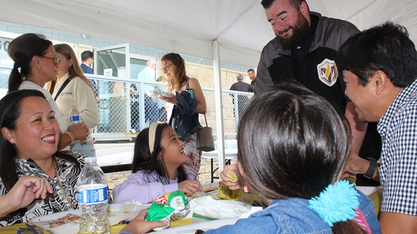 Father Jacob McDaniel, chaplain of St. Teresa of Avila Catholic Student Center in Valparaiso, visits with the Quirante family on Aug. 24 at the annual Back to School Picnic held in the parking lot just off the University of Valparaiso campus. Cecilia (left) and Eugene (right) Quirante enjoyed lunch with their daughters, fifth-grader Bernadette, 11, and fourth-grader Claire, nine, while Father McDaniel invited the girls to an upcoming meeting for prospective altar servers. (Marlene A. Zloza photo)