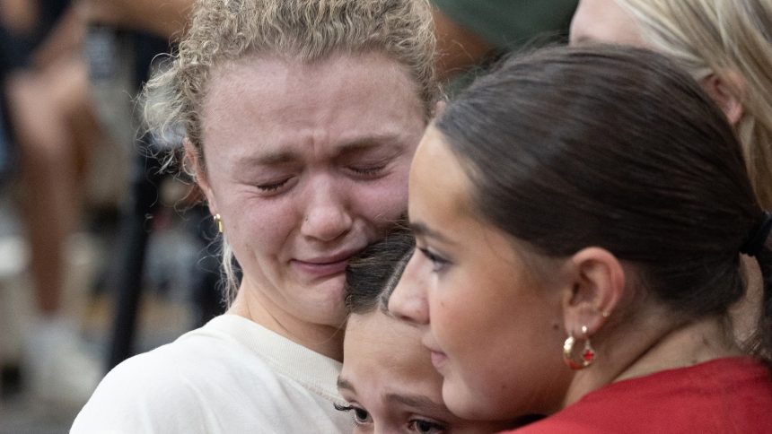 Ellie Mertens, left, youth minister at Annunciation church in Minneapolis, hugs Ella Bradburn (red shirt) and Isabella Manley, who are members of her youth group, during a prayer service at Academy of Holy Angels in Richfield Aug. 27 to support those affected by a shooting at the church that morning. Mertens was inside Annunciation church at the all-school Mass when the shooting occurred. Bradburn and Manley are students at DeLaSalle High School in Minneapolis. (OSV News photo/Dave Hrbacek, The Catholic Spi