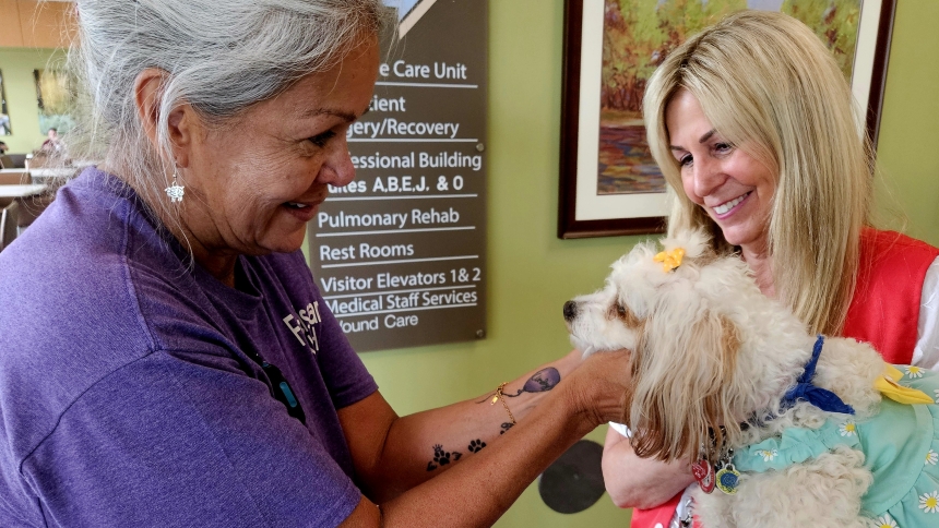 Franciscan Health Munster Environmental Services Associate Diane Sandoval, left, pets Mary Hires’ dog, Molly, during a visit from the Pet Therapy Program earlier this year. 
