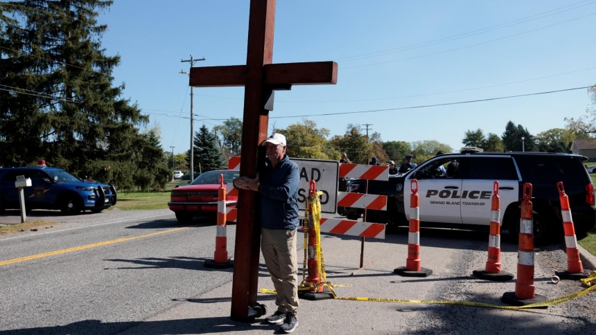 Dan Bradley holds a 10-foot cross near the scene of a mass shooting which took place at the Church of Jesus Christ of Latter-day Saints, in Grand Blanc, Mich., Sept. 29, 2025. (OSV News photo/Rebecca Cook, Reuters)