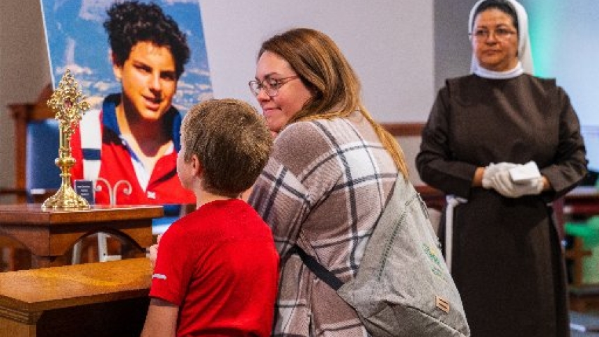 A mother and her son kneel before a first-class relic of St. Carlo Acutis that was on display during St. Carlo Acutis Youth Day Oct. 18, 2025, at the National Shrine of Our Lady of Champion in Wisconsin. St. Carlo, who died Oct. 12, 2006, at age 15, was canonized by Pope Leo XIV on Sept. 7, 2025. (Sam Lucero photo)