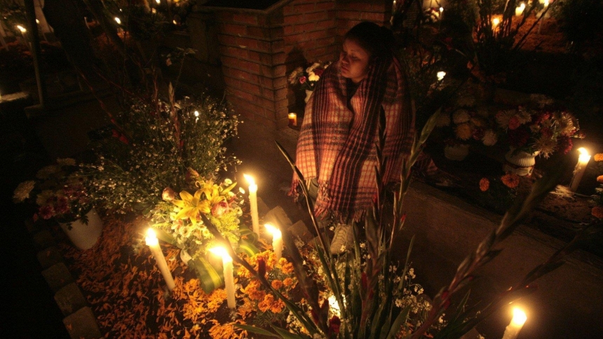 A file photo shows a woman praying at the grave of a relative during the Day of the Dead commemoration near Mexico City. The traditional celebration honors children on All Saints' Day, Nov. 1, and adults on All Souls' Day, Nov. 2. (OSV News photo/Henry Romero, Reuters)