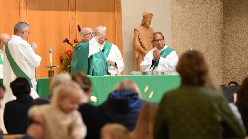 Father Mike Yadron (center),  pastor of St. Thomas More, raises a host during the Eucharistic Prayer at Mass in the Munster Church on Nov. 16. Parish leaders opted to gather for an 80th anniversary celebration of the church’s founding with the recent Mass and brunch, waiting five years after pandemic protocols would have affected a diamond anniversary event. (Anthony D. Alonzo photo) 