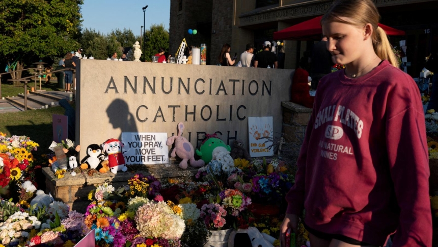 A young woman walks past a memorial outside Annunciation Church in Minneapolis Aug. 30, 2025, which is a home to an elementary school and was the scene of a shooting. The shooter opened fire with a rifle through the windows of the school's church and struck children attending Mass Aug. 27 during the first week of school, killing two and wounding 21 others. (OSV News photo/Tim Evans, Reuters)
