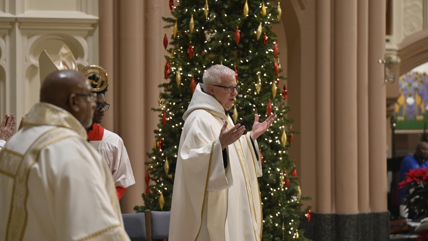 Franciscan Father Michael Surufka (center) makes announcements at the conclusion of Mass on Christmas Eve in the Cathedral of the Holy Angels in Gary. The Dec. 24 liturgy, among the earliest offered in the diocese to celebrate Nativity of the Lord, was presided over by Bishop Robert J. McClory and attended by believers from across the Region. (Anthony D. Alonzo photo)