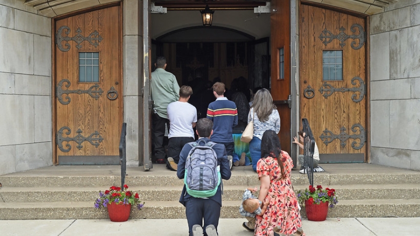 Faithful kneel in front of Cathedral doors