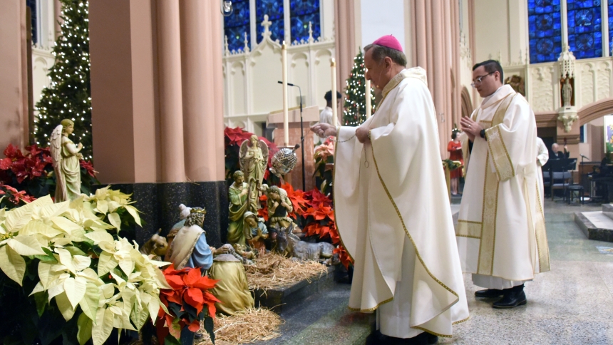 Bishop Robert J. McClory incenses nativity scene statuary displayed near the sanctuary as Deacon Ivan Alatorre (right) watches at the Cathedral of the Holy Angels in Gary during Christmas Vigil Mass on the evening of Dec. 24. Bishop McClory presided at the Mass, which featured beautiful vocal and musical performances, and reminded believers that Bethlehem means "House of Bread," and that from the place of Jesus' birth to the present, Catholics nourish themselves on the Bread of Life. (Anthony D. Alonzo phot