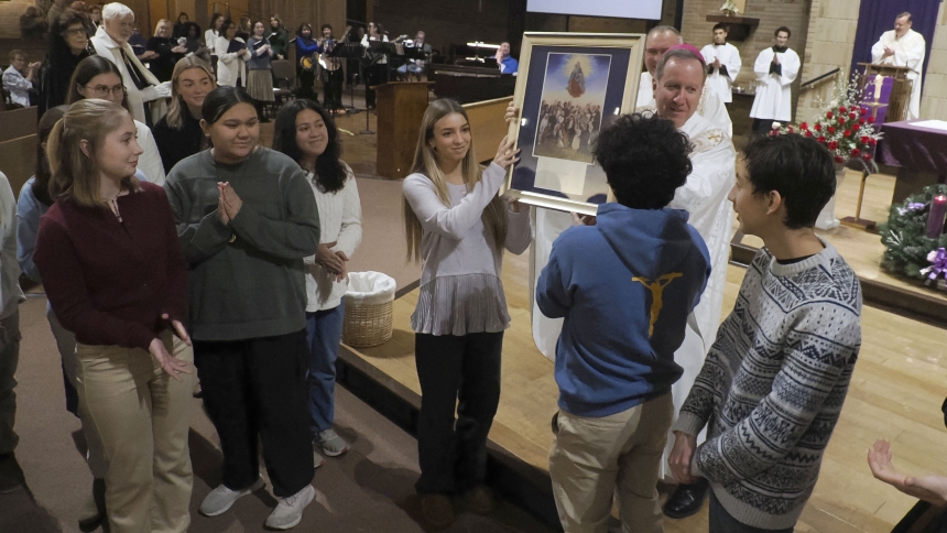 Father David Kime and his sister, Andrea Bojrab, pose in front of Bojrab’s painting, Mary, Queen of All Saints that was unveiled and blessed by Bishop Robert J. McClory on Dec. 8. (Deacon Bob Wellinski photo)