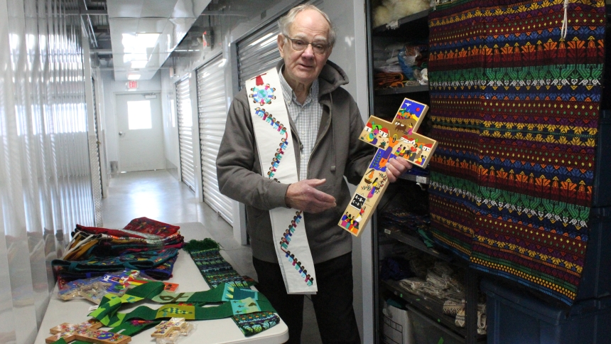 Tom Hocker of Tree of Life Imports displays crosses, stoles and tote bags that he imports from El Salvador and Guatemala as part of his fair trade business. All are handmade and embroidered by local artisans. (Marlene A. Zloza photo)
