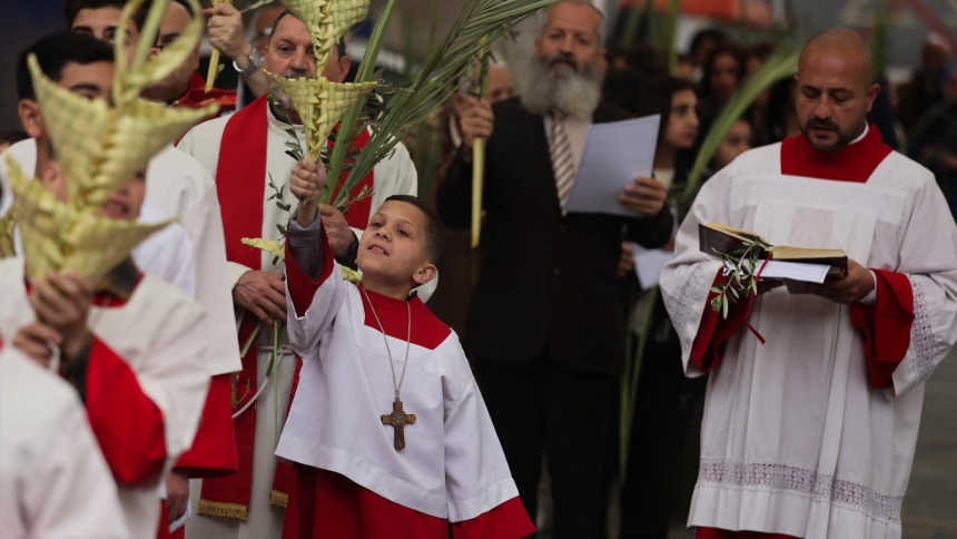 A young altar server raises a palm frond during Palm Sunday Mass at Gaza City's Holy Family Church March 29, 2026. (OSV News photo/Dawoud Abu Alkas, Reuters)