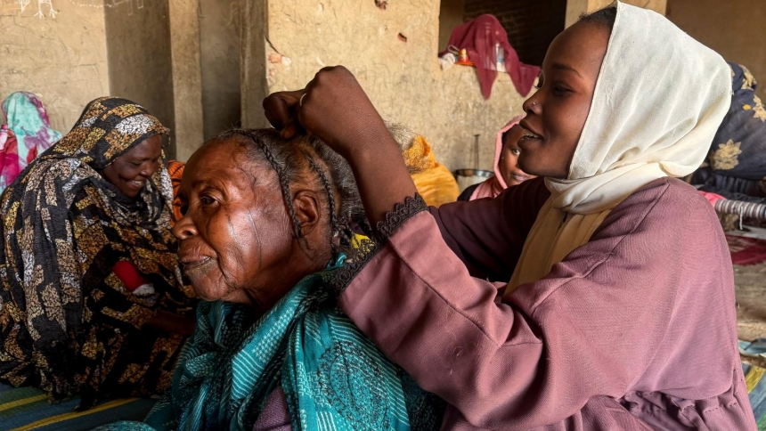 A displaced South Sudanese woman braids her grandmother's hair Jan. 15, 2026, at a shelter in El Obeid, in Sudan's North Kordofan state. In a March 26, 2026, message Italian Bishop Christian Carlassare of Bentiu, South Sudan, said his people are living a real-life Way of the Cross, marked by suffering, violence and deep wounds.(OSV News photo/El Tayeb Siddig, Reuters)