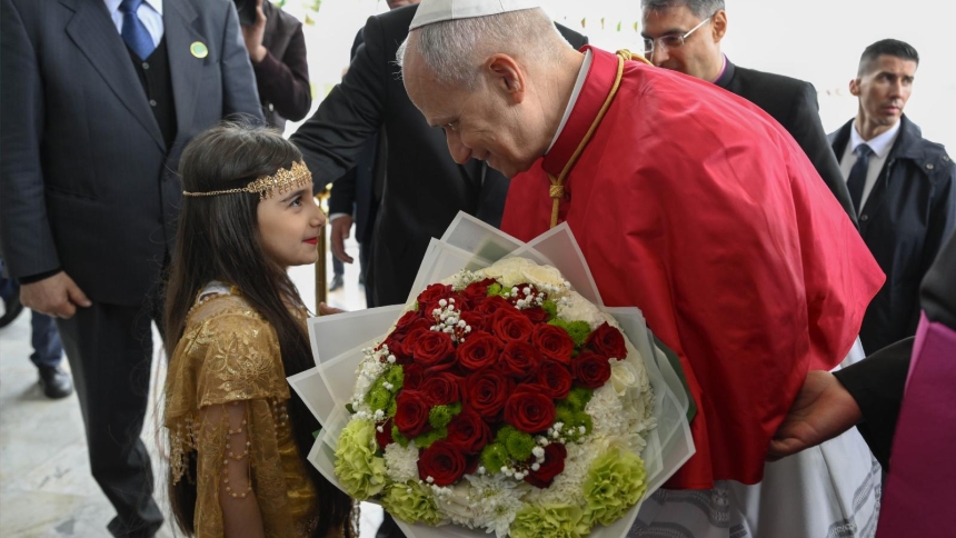 Pope Leo XIV is greeted by an Algerian girl with flowers upon arrival at Houari Boumediene International Airport in Dar El Beida district in Algiers, Algeria, April 13, 2026, to begin his apostolic journey to Algeria, Angola, Cameroon and Equatorial Guinea. (OSV News photo/Simone Risoluti, Vatican Media)