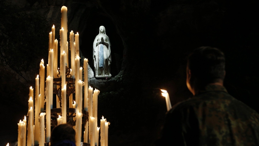 Candles are seen around a statue of Mary in the grotto at the Shrine of Our Lady of Lourdes in France in this file photo. (CNS photo/Paul Haring)