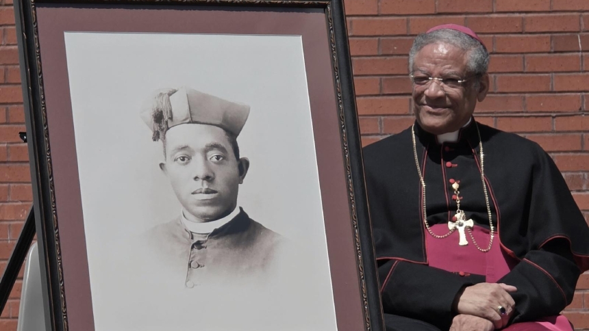 Retired Chicago Auxiliary Bishop Joseph N. Perry sits next to a portrait of the first African American priest of the U.S., Father Augustus (Augustine) Tolton, during the announcement April 29, 2026, on the shrine to the priest planned for St. Boniface Church in Quincy, Ill. (OSV News photo/courtesy Diocese of Springfield)