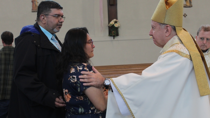 Bishop Robert J. McClory comforts parents Julio and Iliana Fonseca, of Munster, as he presents them with a lit candle in remembrance of their son, Julio Camilo Fonseca, who died in 2014, three days after his birth. The couple, with their two daughters, attended the annual Pregnancy and Infant Loss Memorial Mass hosted by the Diocese of Gary on May 3 at St. John Bosco in Hammond. (Marlene A. Zloza photo)