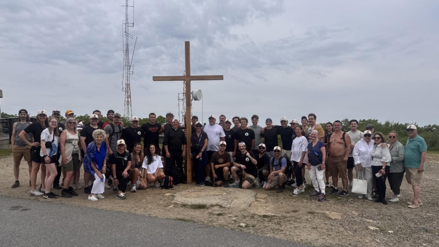 Noah Hajdu, a 23-year-old resident of Sterling, Mass., Father Derek A. Mobilio, pastor of Our Lady of the Angels Parish in Worcester, and others pose with the cross atop Wachusett Mountain in Westminster June 6, 2026. (OSV News photo/courtesy)