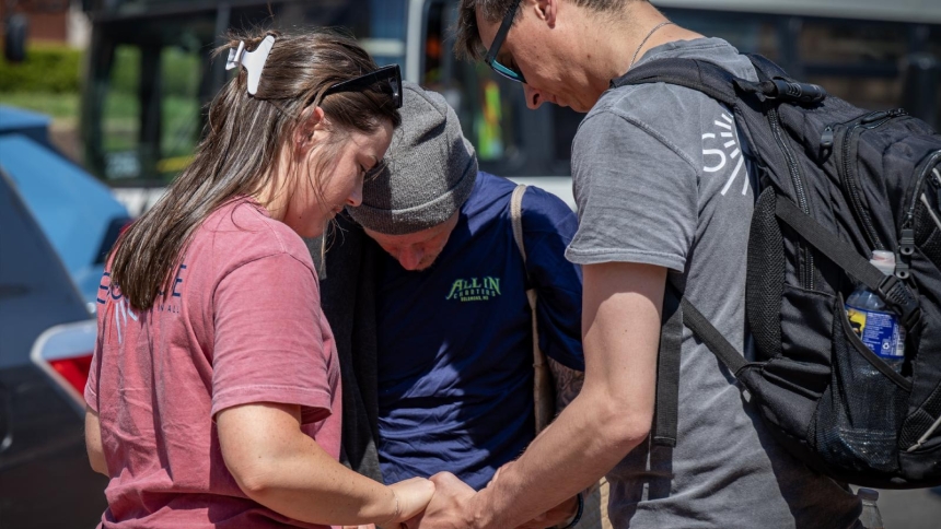 Source of All Hope missionaries Erin Kelter, left, and Daniel Otto, right, pray with Keith Quigg, a man experiencing homelessness, at the corner of Greene and West Lombard streets in Baltimore April 14, 2026. (OSV News photo/Kevin J. Parks, Catholic Review)