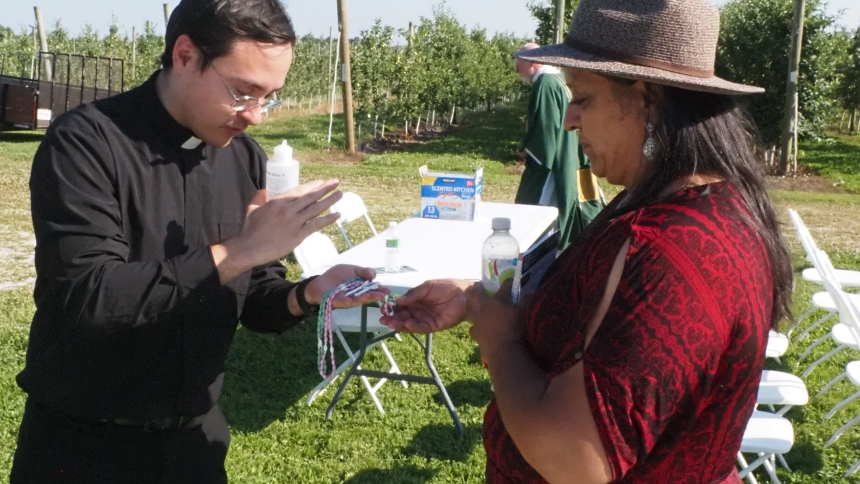 Father Ivan Alatorre blesses Rosaries following the Mass for Migrant Workers at Garwood Orchards on July 12. (Michael Wellinski photo)
