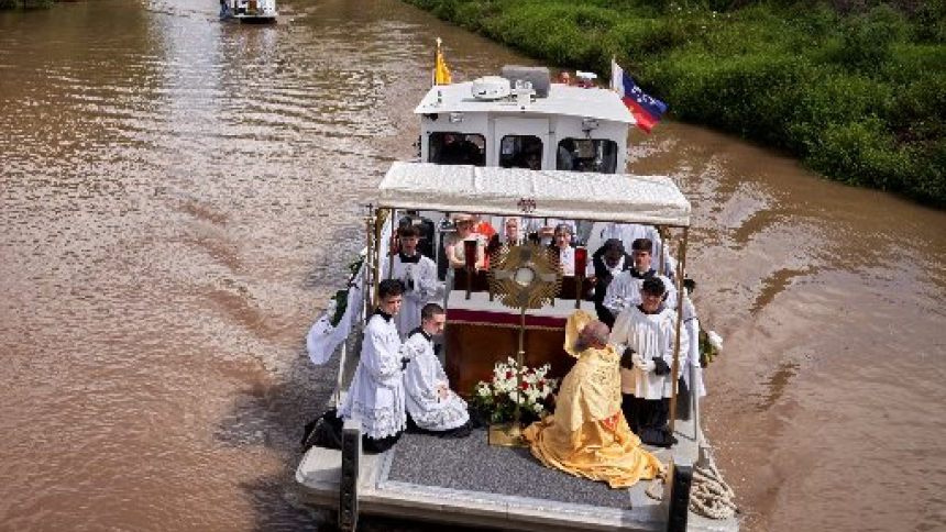 A clergyman kneels before a monstrance as worshippers take part in the an annual 40-mile Fête-Dieu du Teche Eucharistic boat procession held on Aug. 15, 2026, along Louisiana's historic Bayou Teche. It commemorates the Feast of the Assumption and retraces the historic 1765 migration journey of the Acadian (Cajun) people from Leonville to St. Martinville. (OSV News photo/courtesy Chris Lancon)