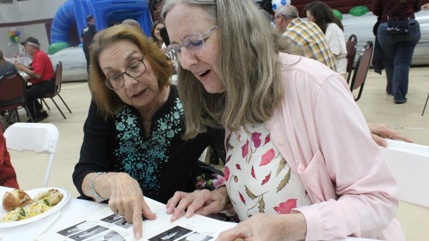 Rosemary Wojdyla (left), a 1973 graduate of Calumet College of St. Joseph, shows her senior class yearbook to Linda Kalwinski, who wanted to look up her husband, Mark Kalwinski, also a CCSJ alumna, during the Whiting school’s 75th Birthday Bash on Sept. 19. Hundreds of students, alumni, faculty, staff and their families attended. (Marlene A. Zloza photo)