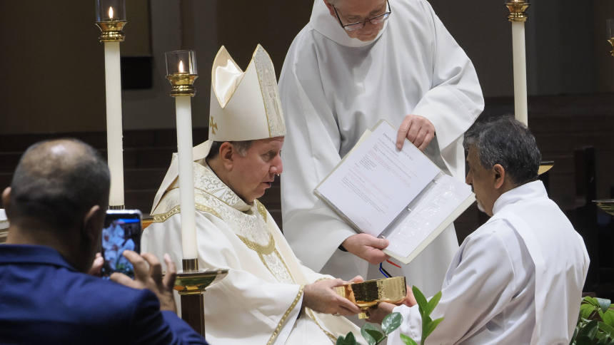 Bishop Robert J. McClory hands a ciborium to diaconate candidate Manuel Pena as Father Marty Dobrzynski holds the book during the Deacon Jubilee Mass that also included the Rite of Acolyte for the five diaconate candidates. (Deacon Bob Wellinski photo)