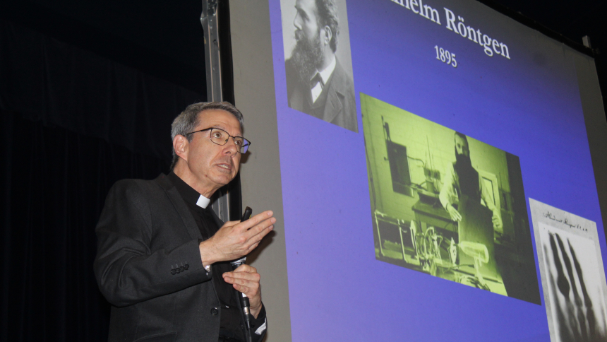 Father John Kartge, an astrophysicist, biblical scholar and, since 2015, rector/president at the University of St. Mary of the Lake/Mundelein Seminary, explains how scientist Wilhelm Rontgen (on the screen) pursued a mystery in his 1895 cathode ray tube research that led to the invention of x-rays. “Good scientists don’t ignore a mystery, they stay with it,” said the Bishop Noll Institute alumnus who retired to the Hammond high school on Sept. 2 at the invitation of the Indiana Knights of Columbus to discus