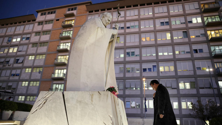 A man prays in front of a statue of the St. John Paul II outside Gemelli Hospital in Rome Oct. 13, 2026, where Pope Leo XIV had surgery that afternoon to remove a lung nodule. The Vatican confirmed that evening that Pope Leo has lung cancer. (OSV News photo/Matteo Minnella, Reuters)